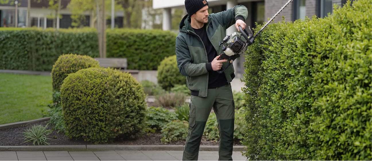 Mann in Sobral Arbeitskleidung schneidet mit der Heckenschere eine Hecke im Vorgarten