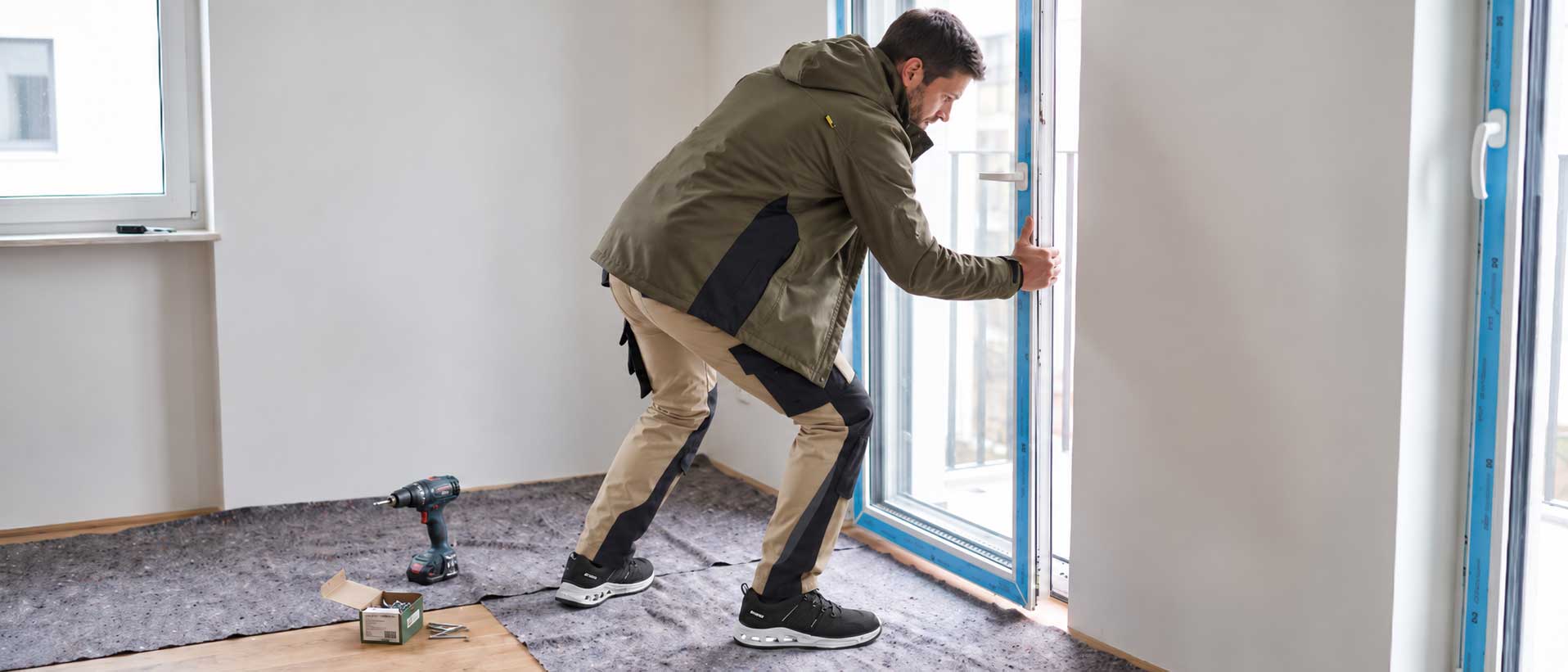 Handwerker bei der Fenstermontage in Arbeitskleidung