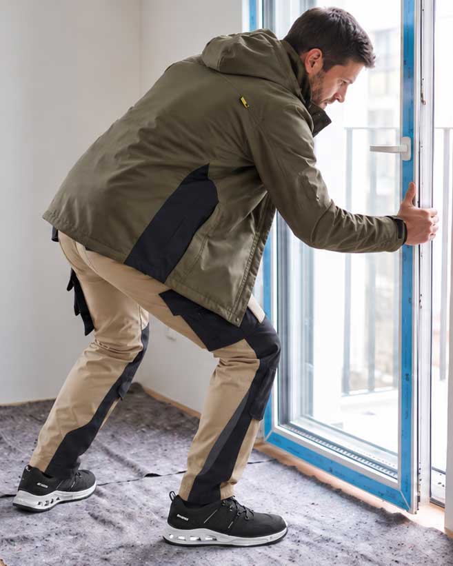 Handwerker bei der Fenstermontage in Arbeitskleidung